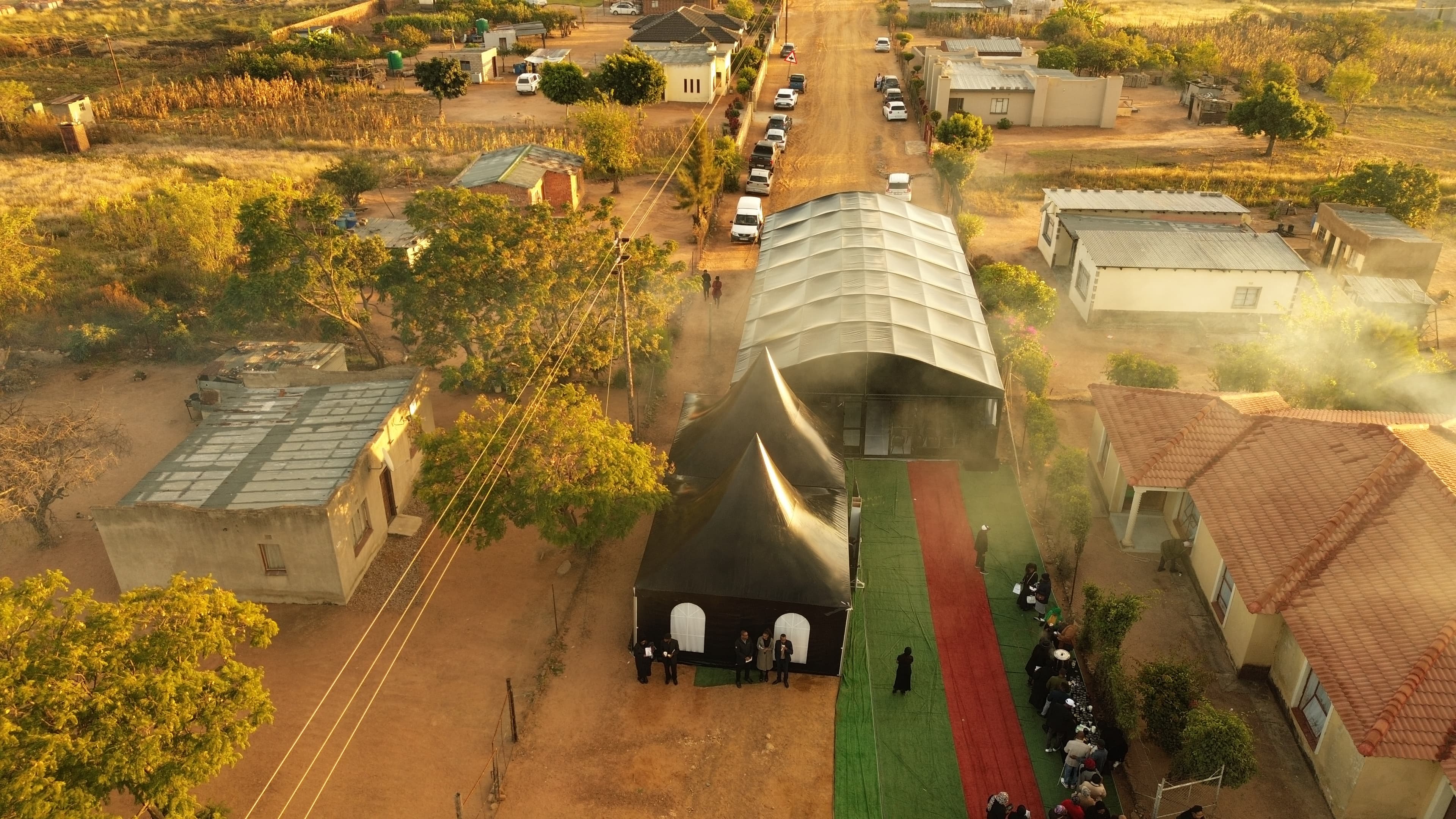 Aerial drone view of large outdoor event setup with marquee tents arranged across a scenic South African landscape